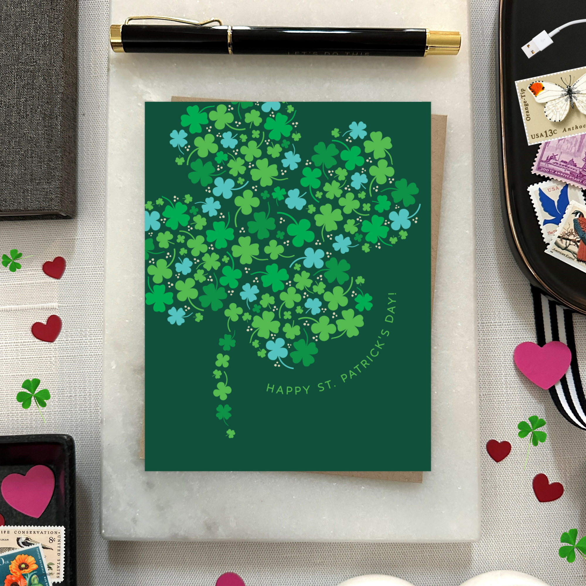 A st. patricks day greeting card with a pattern of tiny illustrated shamrocks arranged in the shape of a larger four-leaf clover, and the text 'Happy St. Patrick's Day' 