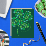 A st. patricks day greeting card with a pattern of tiny illustrated shamrocks arranged in the shape of a larger four-leaf clover, and the text 'Happy St. Patrick's Day' 