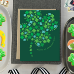 A st. patricks day greeting card with a pattern of tiny illustrated shamrocks arranged in the shape of a larger four-leaf clover, and the text 'Happy St. Patrick's Day' 