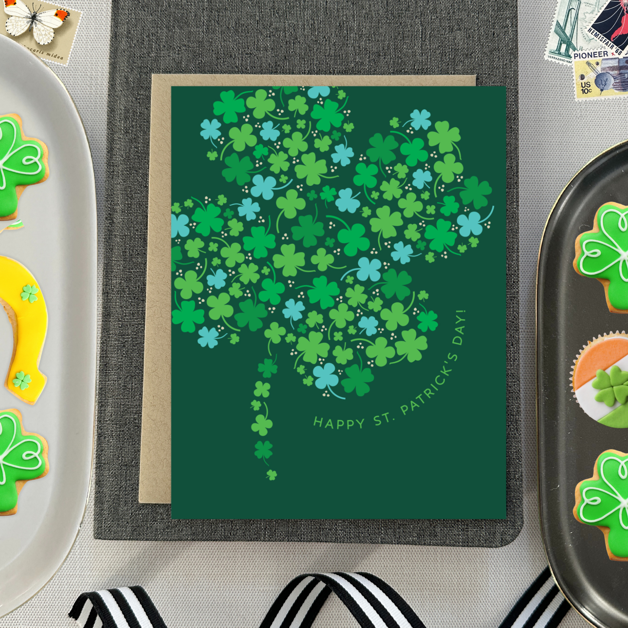 A st. patricks day greeting card with a pattern of tiny illustrated shamrocks arranged in the shape of a larger four-leaf clover, and the text 'Happy St. Patrick's Day' 