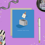 A playful birthday greeting card with an illustration of a smiling slice of toast with a party hat popping out of a toaster, and the text 'A Birthday Toast to You!'.